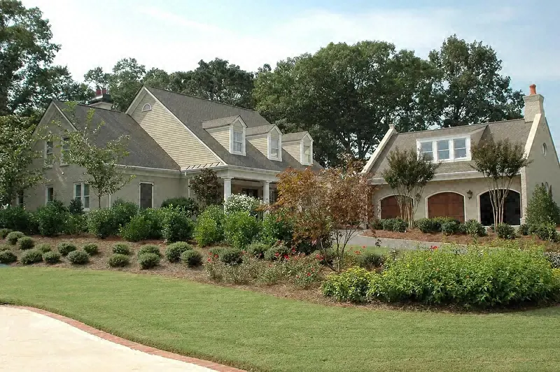 Neighborhood street with landscaped front yards, trimmed shrubs and green lawns